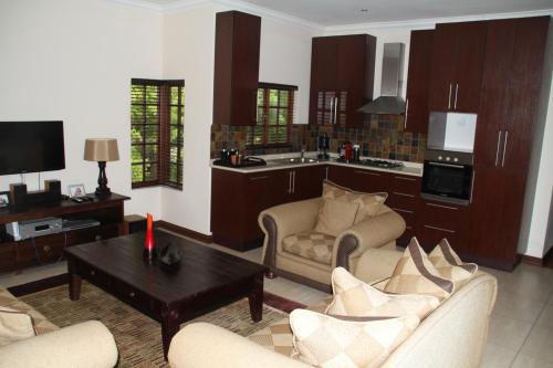 sala de estar con sofás, mesa y cocina en White River Country Estate Self Catering Apartment, en White River