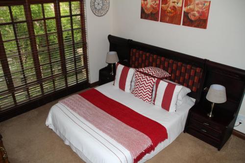 a bedroom with a bed with red and white pillows at White River Country Estate Self Catering Apartment in White River