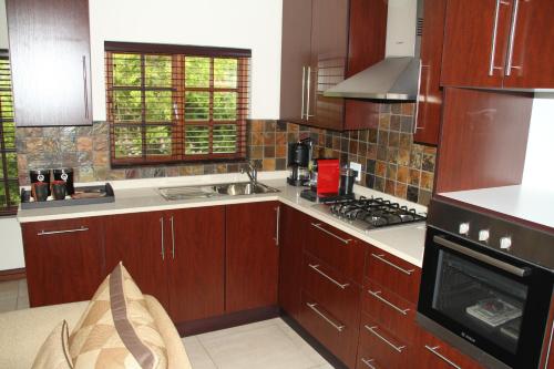 uma cozinha com armários de madeira e um forno com placa de fogão em White River Country Estate Self Catering Apartment em White River