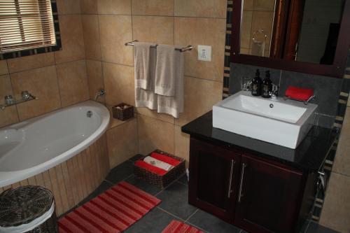 a bathroom with a tub and a sink and a bath tub at White River Country Estate Self Catering Apartment in White River