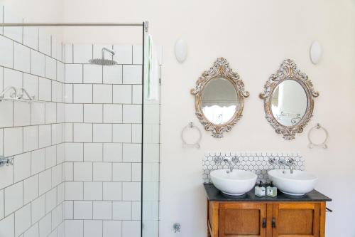 uma casa de banho com dois lavatórios e espelhos na parede em Herberg Manor em Somerset East