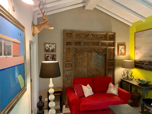 a living room with a red couch and a door at Casa Stardust & cottages in Quelfes