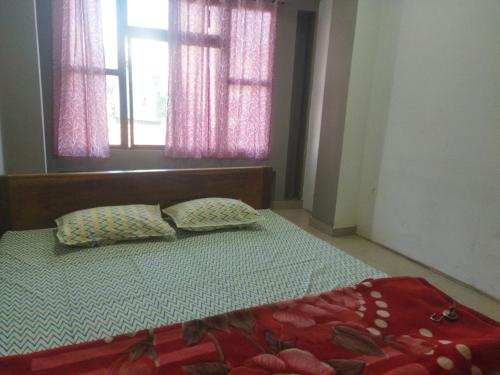 a bedroom with a bed with two pillows and a window at OYO HOTEL RASU in Imphal