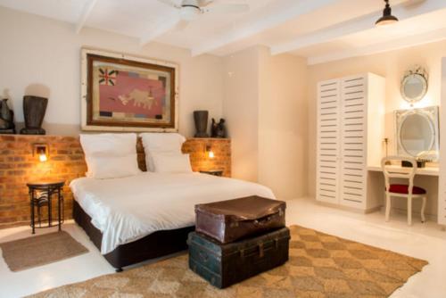 a bedroom with a white bed with a trunk in it at Emily Moon River Lodge in Plettenberg Bay