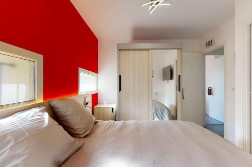 une chambre avec un grand lit avec un mur rouge dans l'établissement 04.Studio#Creteil#Loft#Cinéma, à Créteil