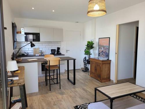 a kitchen with a table and chairs in a room at L'Escapade T1 de 30 m2 neuf. in Granville