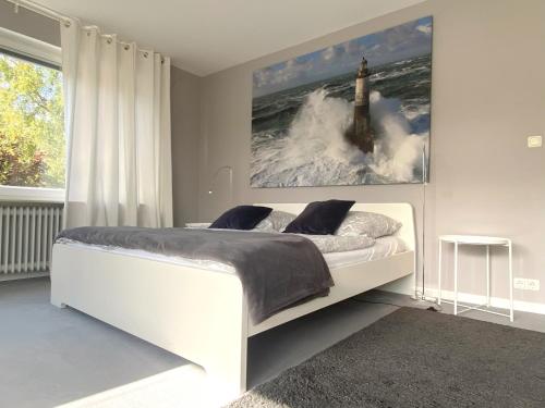 ein Schlafzimmer mit einem weißen Bett und einem Gemälde an der Wand in der Unterkunft The Kreideberger - Haus mit Platz in Lüneburg