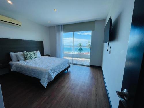 a bedroom with a bed and a view of the ocean at Puerto Azul Hotel in Puntarenas
