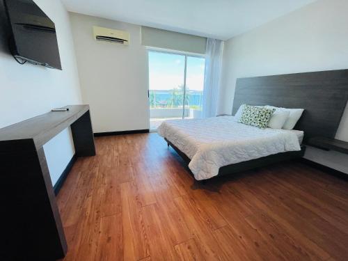 a bedroom with a bed and a large window at Puerto Azul Hotel in Puntarenas