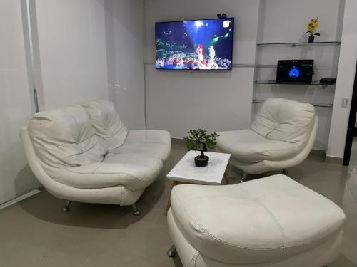 a waiting room with two white chairs and a tv at Apartamento en Cartagena Makrotours in Cartagena de Indias