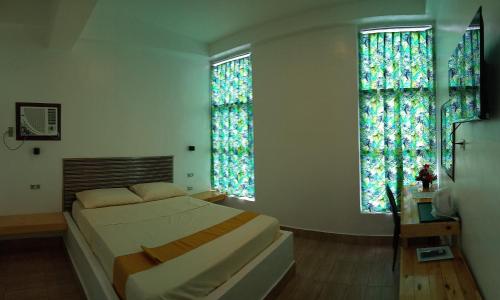 a bedroom with a bed and two large windows at BBoutique Hotel in Lapu Lapu City