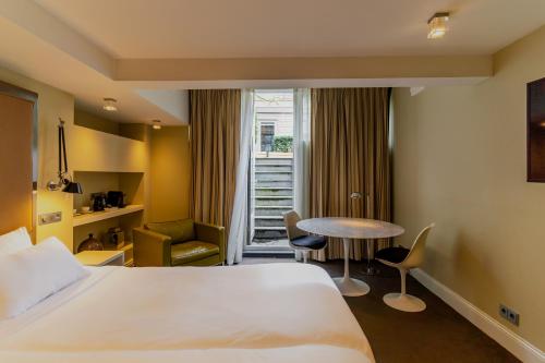 ein Hotelzimmer mit einem Bett, einem Tisch und einem Fenster in der Unterkunft Hotel Roemer Amsterdam in Amsterdam