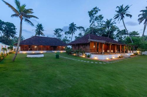 a house with a green lawn in front of it at Deshadan's Tarangi Beach Villas,Marari in Mararikulam