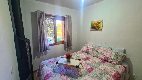 a bedroom with a bed and a table with flowers on it at Chalé Sitio Carazal - Paz e Sossego junto a Natureza 
