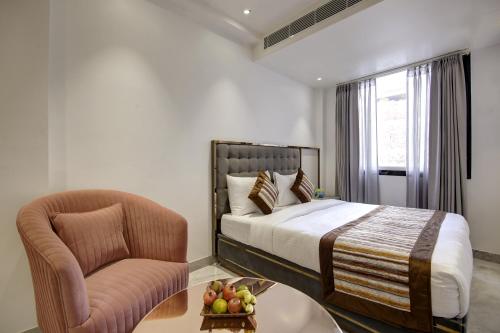 a bedroom with a bed and a chair and a table at Hotel Kaca Inn-by Haveliya Hotels in New Delhi