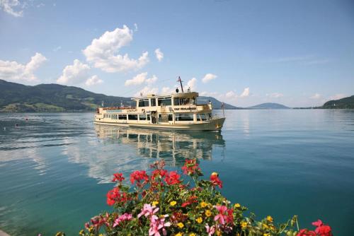 a boat on the water with flowers in the foreground at Appartement Krippenstein mit Indoorpool und Sauna in Bad Goisern