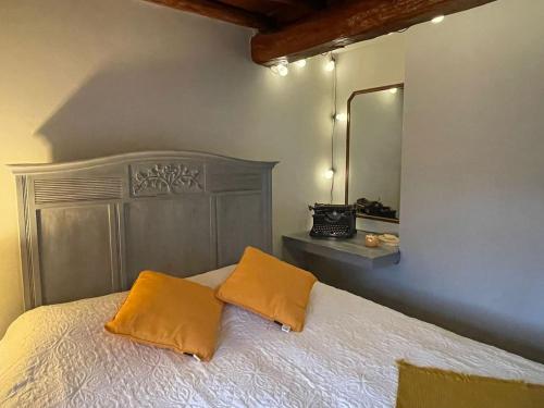 een slaapkamer met een bed met 2 kussens en een spiegel bij Het Houwershuuske in Reijmerstok