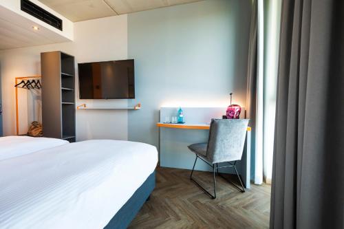 a room with two beds and a chair and a tv at LOGINN Hotel Waiblingen in Waiblingen
