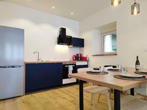 a kitchen with a wooden table and a refrigerator at Cœur de ville, spacieux appartement rez de jardin in Paimpol