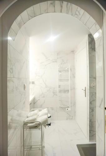 une salle de bain avec des murs en marbre blanc et un tabouret dans l'établissement Exquisite tiny house with garden and air con - between Paris-Disneyland - 3mins from train station, à Noisy-le-Grand