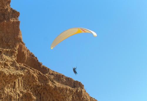 a person flying a parachute over a mountain at Riad Sahara Sunset Beach Douira Agadir in Douaïra
