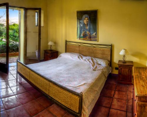 a bedroom with a large bed with a painting on the wall at Casale il Pozzo in Sciacca