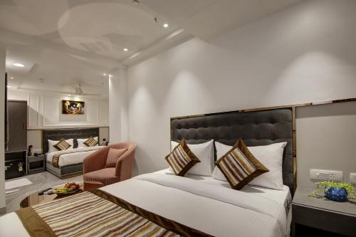 a hotel room with two beds and a chair at Hotel Kaca Inn-Traveller's Choice Awarded Best of the Best 2025 in New Delhi