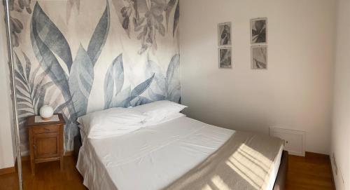 ein Schlafzimmer mit einem weißen Bett mit Wandmalereien in der Unterkunft L'Ulivo Selvatico in Brandizzo