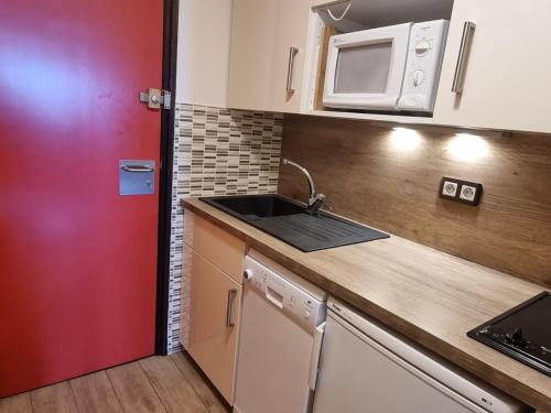 une cuisine avec un évier et un micro-ondes dans l'établissement Studio rénové skis aux pieds, balcon vue Mont-Blanc, 4 pers. - FR-1-181-2558, à Aime La Plagne
