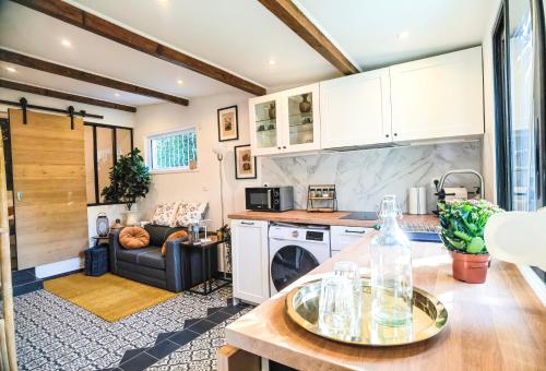 uma cozinha e sala de estar com armários brancos e uma mesa em Exquisite tiny house with garden and air con - between Paris-Disneyland - 3mins from train station em Noisy-le-Grand