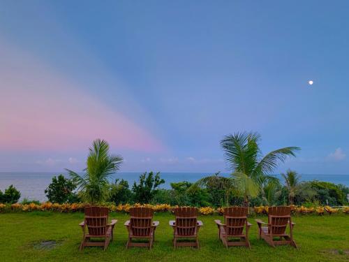 a group of chairs sitting in the grass near the ocean at Taitung Blue Sea Villa in Chenggong