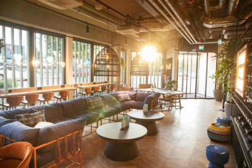 a large room with couches and tables and windows at LOGINN Hotel Waiblingen in Waiblingen