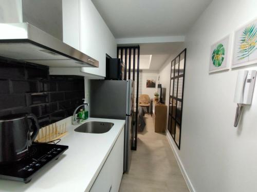 a kitchen with a sink and a refrigerator at The Aces Crib at Azure North Pampanga in San Fernando