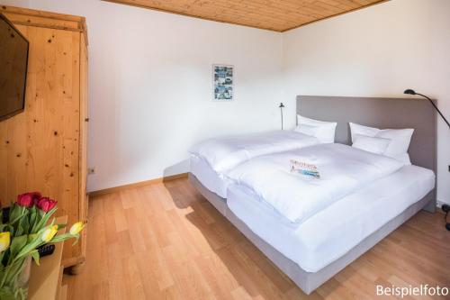 ein großes weißes Bett in einem Zimmer mit einem TV in der Unterkunft Birkenhof in Norderney