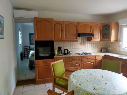 a kitchen with wooden cabinets and a table with green chairs at Logis51 in Ville-sur-Tourbe