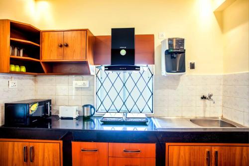 cocina con armarios de madera y encimera negra en 'Golden Sea Shell' 1 bhk Beach apartment en Benaulim