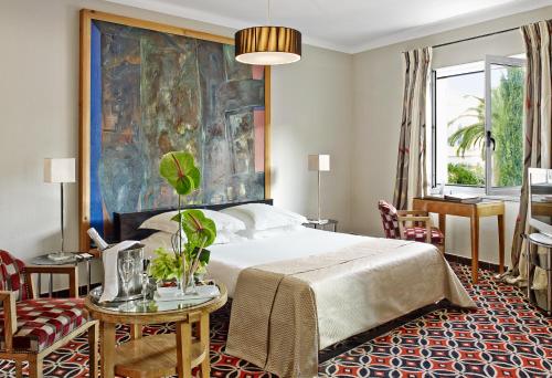 a bedroom with a bed and a large painting on the wall at Hôtel Belles Rives in Juan-les-Pins