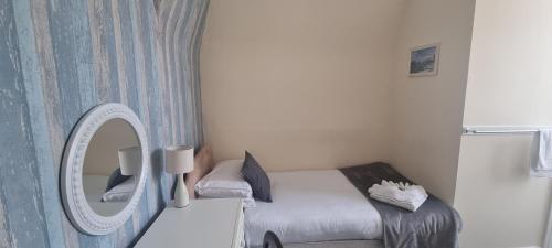 a small bedroom with a bed and a mirror at Royal Pier in Sandown