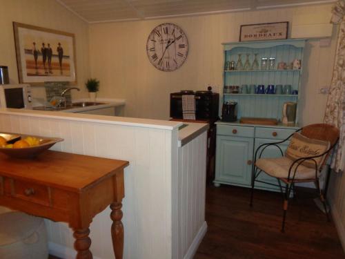 a kitchen with a counter and a clock on the wall at Log Cabin, Conveniently Situated halfway between Stratford and Warwick in Stratford-upon-Avon