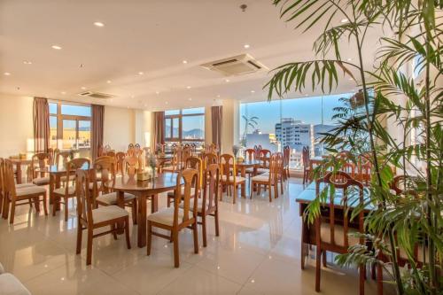 Sunview Beach Hotel Danang في دا نانغ: مطعم بطاولات وكراسي ونوافذ كبيرة