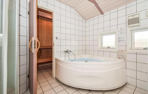 a white tub in a white tiled bathroom at Nice Home In Haderslev With Kitchen in Kelstrup Strand