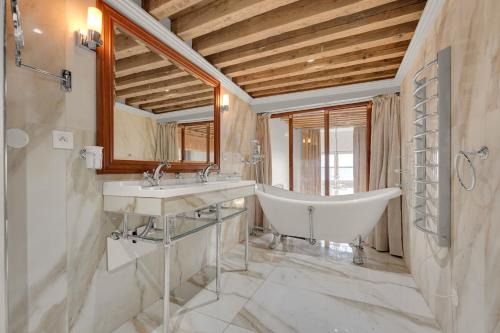 a bathroom with two sinks and a tub and a mirror at Les Relais du Capitole in Toulouse