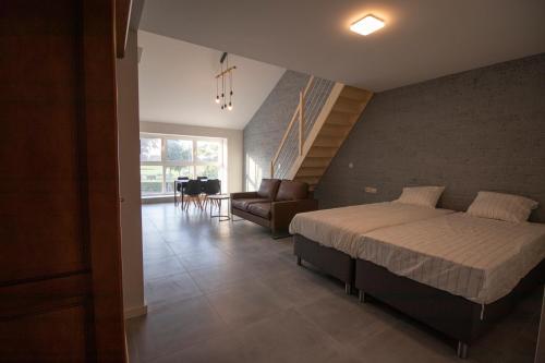 een slaapkamer met een bed, een bank en een trap bij De Hoog Velden 13 in Neerpelt