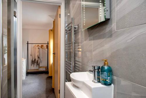 ein Badezimmer mit einem weißen Waschbecken und einem Spiegel in der Unterkunft Country Cottage in quaint Village, sleeps 3 in Bere Alston