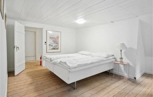 Cozy Home In Nstved With Kitchen في نايستفيد: غرفة نوم بيضاء بسرير كبير ومصباح