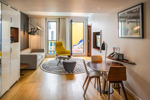 a living room with a table and yellow chairs at Molitor Hôtel & Spa Paris - MGallery Collection in Paris