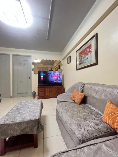 Il comprend un salon doté d'un canapé et d'une télévision à écran plat. dans l'établissement AZ Suites 2 bedroom Camella Northpoint, à Davao