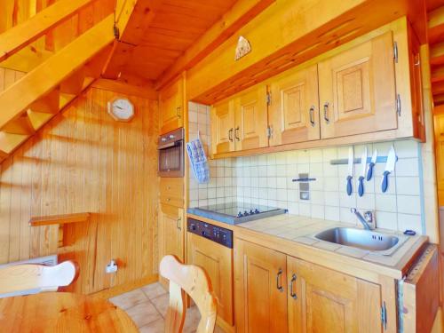 une cuisine avec des armoires en bois, un évier et une table dans l'établissement Appartement 3 pièces familial - Les Saisies - FR-1-594-45, à Hauteluce