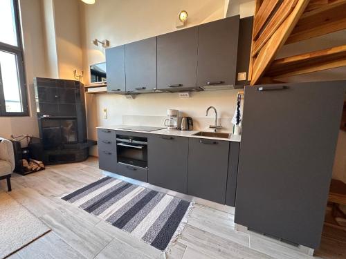 a kitchen with gray cabinets and a sink and a stove at HolySuites 2 - Ski-in and out apartment in the middle of ski slopes in Pyhä in Pyhätunturi