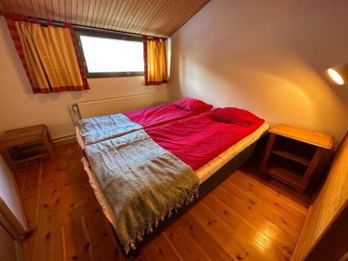 a small bedroom with a bed with a red blanket at HolySuites 2 - Ski-in and out apartment in the middle of ski slopes in Pyhä in Pyhätunturi